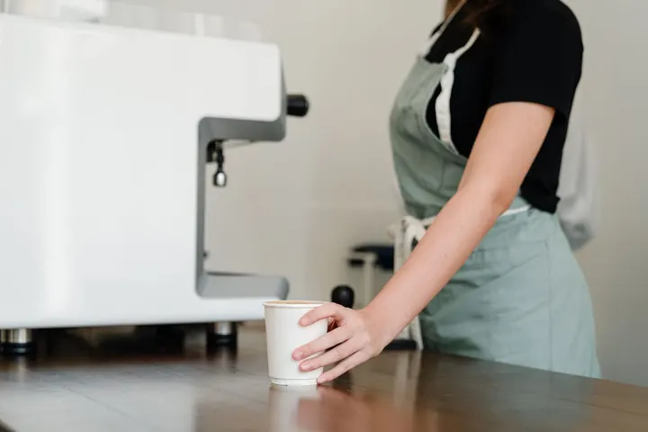 Barista entregando un café en el mostrador de una cafetería