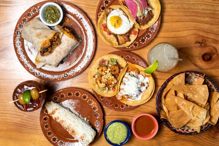Mesa con tacos, quesadillas y salsas servidos en platos de barro