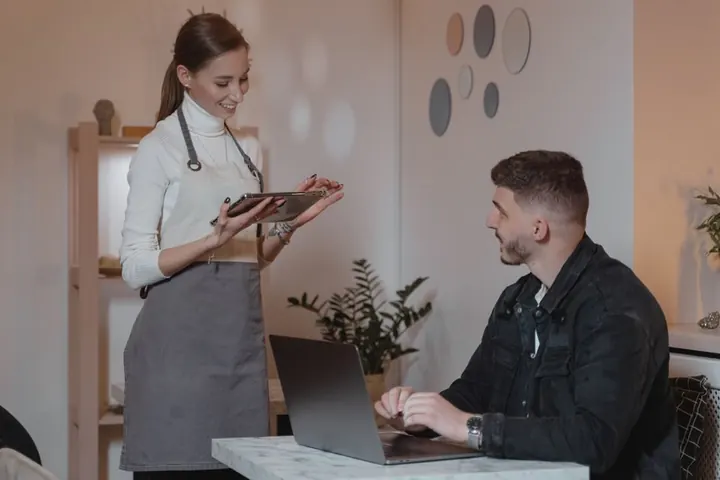 Mesera con una tablet atendiendo a un cliente en un café